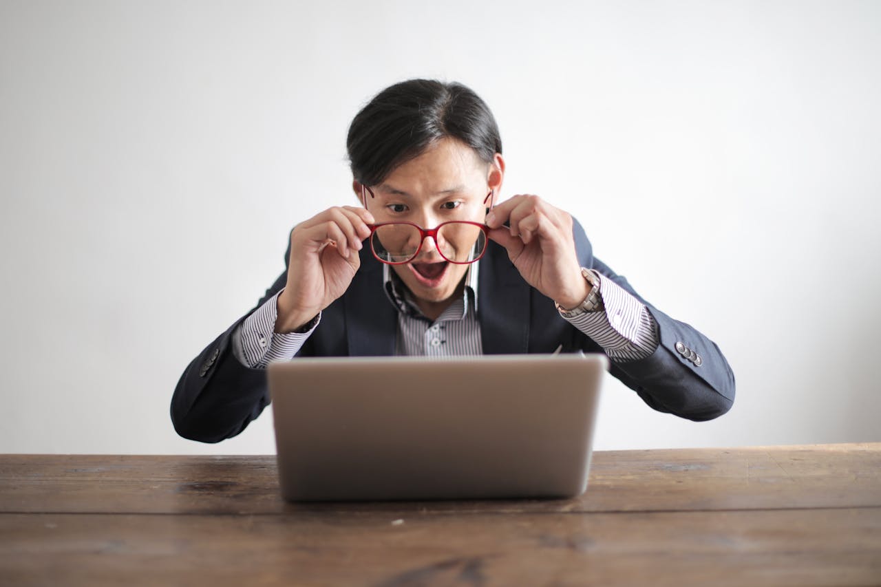 Surprised man in a suit looking at laptop, expressing disbelief indoors.